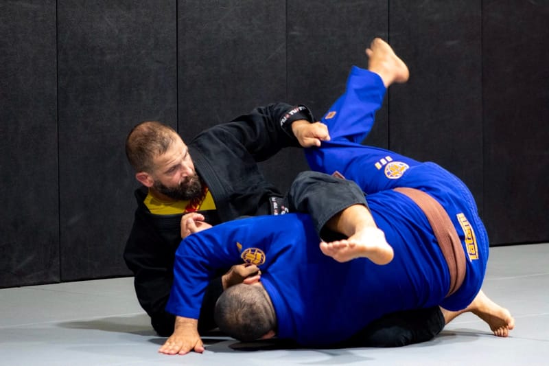 An adult controlling the legs to pass guard