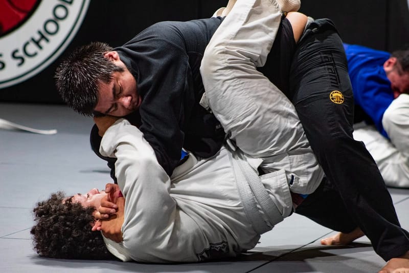 An adult in a black gi passing a partner's guard