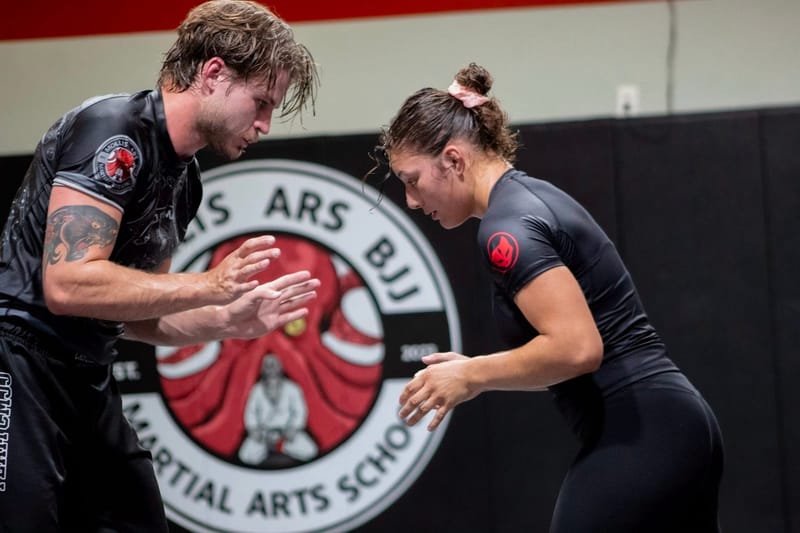 A man and woman drilling no-gi in Mollis Ars rashguards