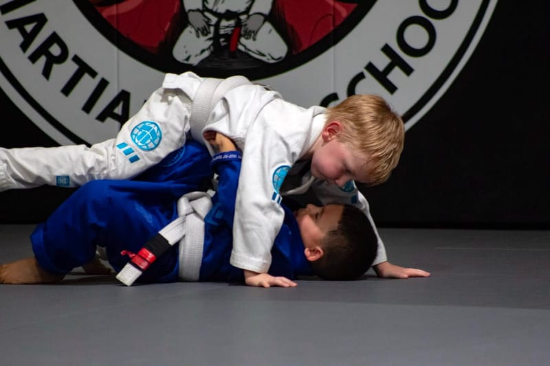Two boys rolling from guard in white gis