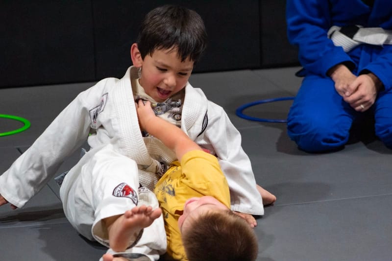 Two boys rolling and laughing on the mat