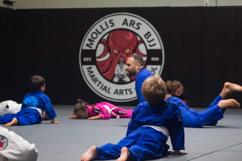 Kids warming up with shrimping drills under the Mollis Ars logo