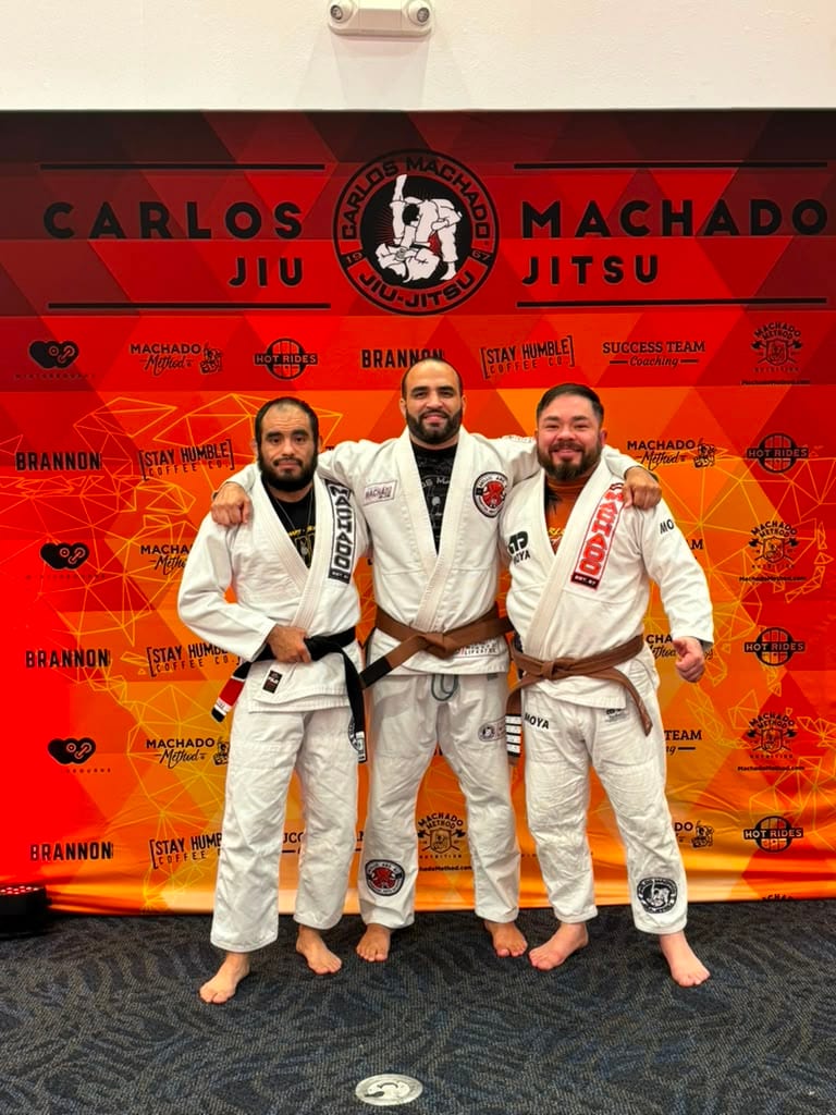 The Mollis Ars BJJ team standing in front of the Carlos Machado banner