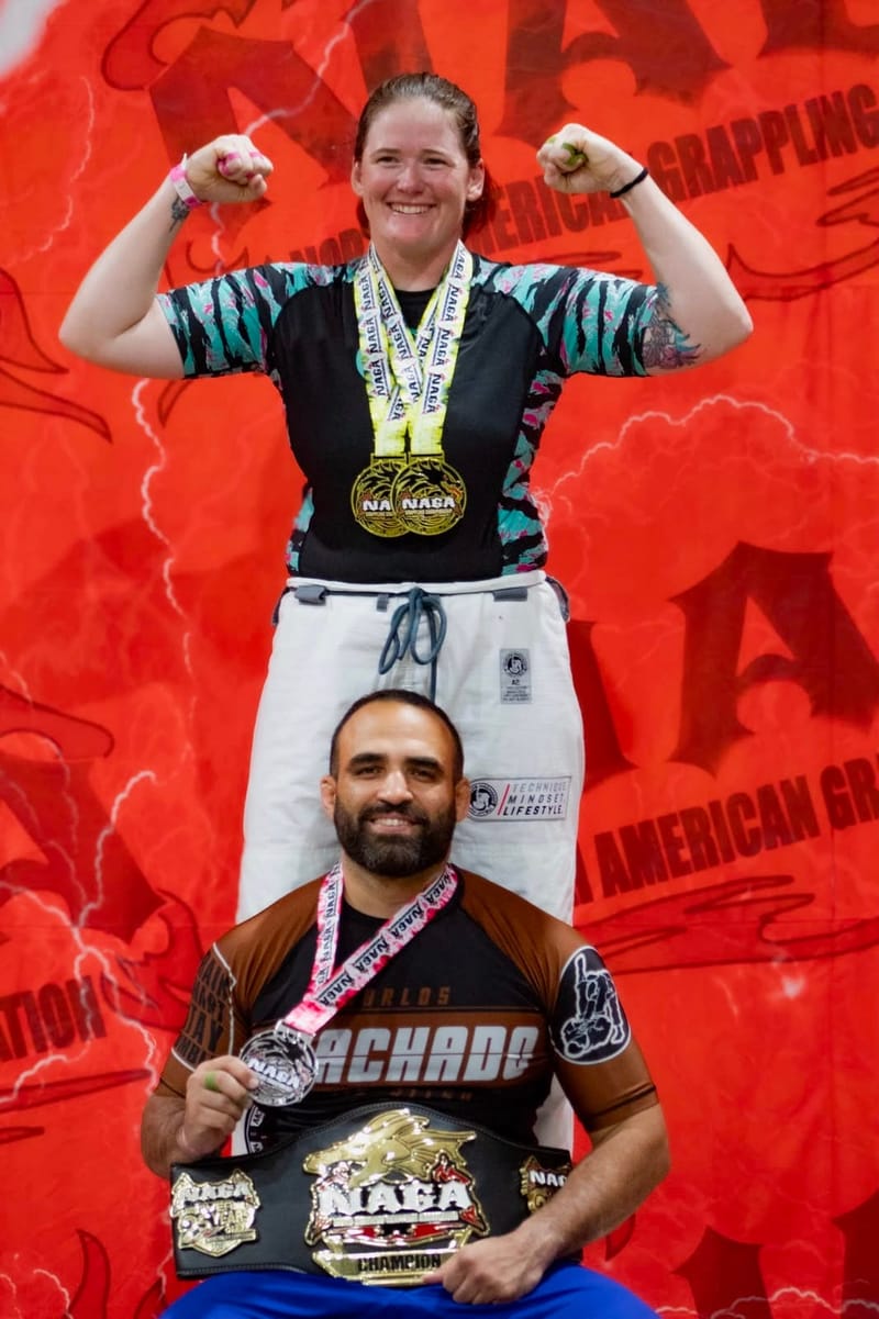 Team members on the podium with NAGA medals and a championship belt