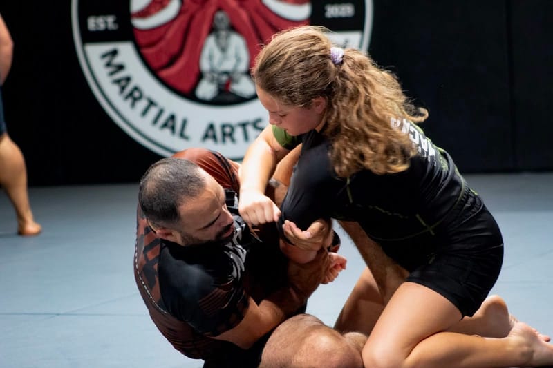 A teen girl grappling no-gi with a coach